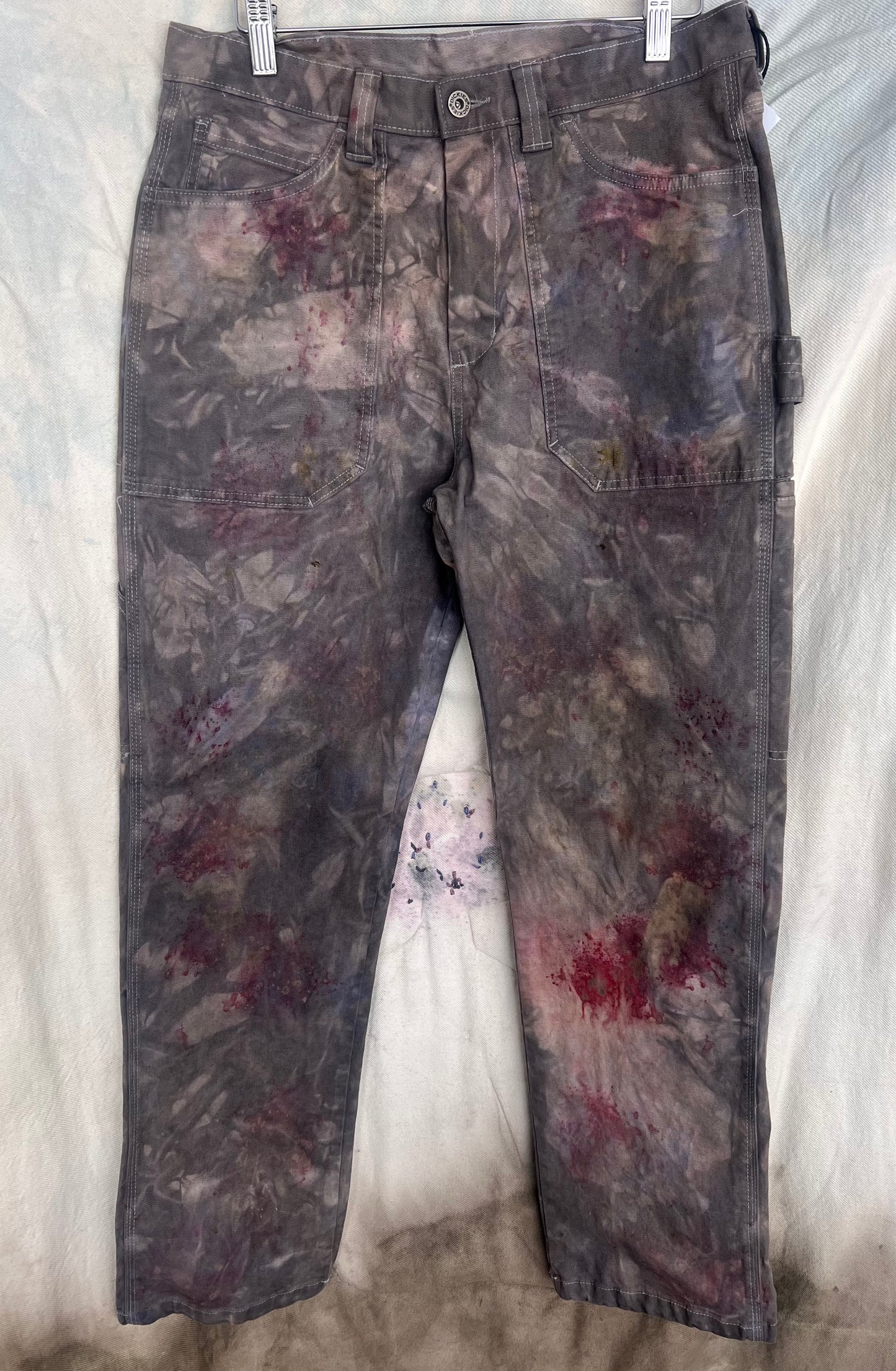 Floral-patterned naturally dyed pants hanging against a neutral background