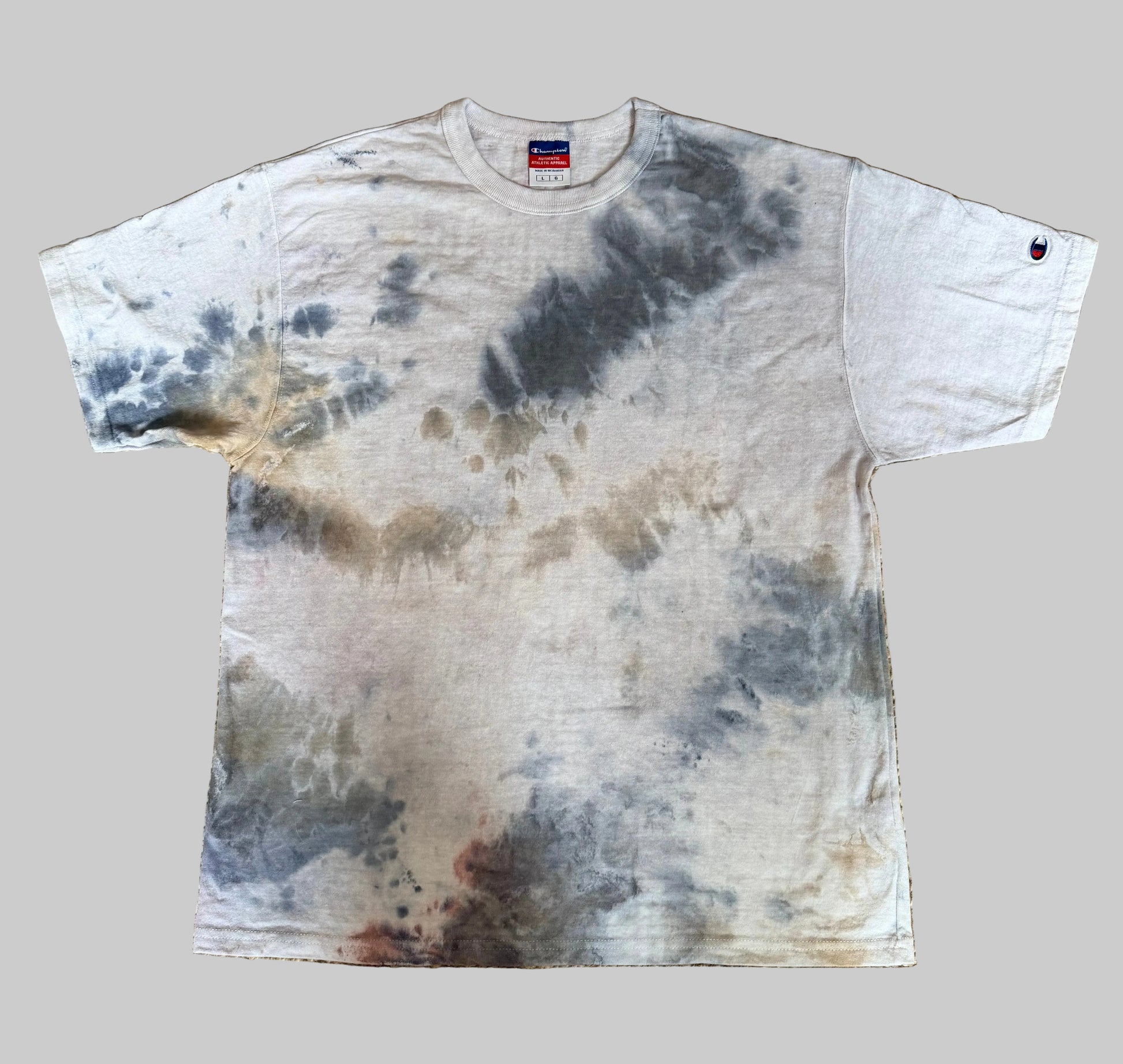 Tie-dye t-shirt with a pattern of dark and light shades on a textured beige surface