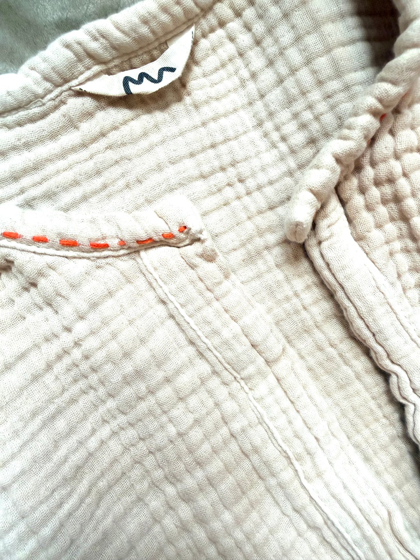 beige dress with orange embroidery along neckline